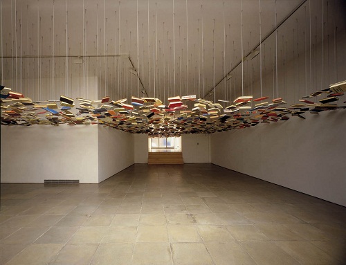 An empty room with a cloud of second-hand books suspended from the ceiling