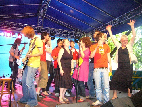 A colourful group of people singing and dancing on an outdoor stage