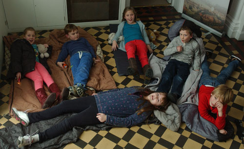 A group of children lying on a museum floor with sleeping bags and torches