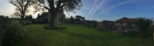 A panoramic photo of a country house in beautiful grounds at dusk